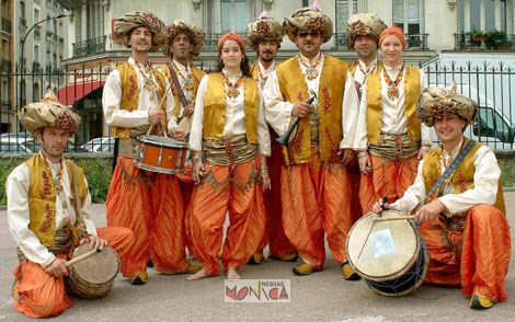 Le groupe aux influences rai est habille de costumes oranges et or avec des turbans