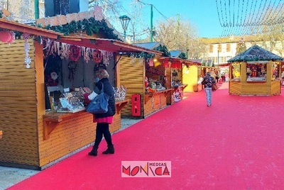 Village de noel dans une zone pietonne de centre-ville avec chalets pliables, decoration, guirlande, et un pere noel