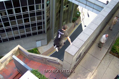 Un traceur vue de dos saute d'un toit d'immeuble sous les yeux ebahis de passants