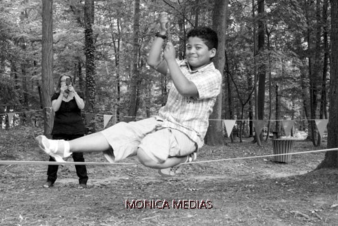 Un enfant s'initie au slackline a l'aide d'une corde et realise une figure avec une jamble pliee et l'autre tendue