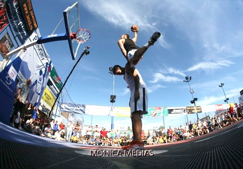 Deux basketteurs sous le panier de basketball font un smash lors d’un spectacle de dunk basket en plein air