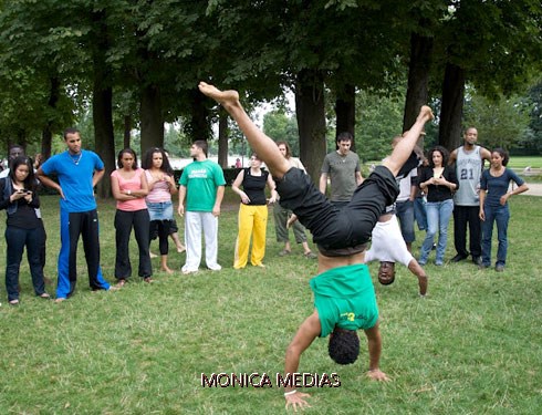 Un capoeiriste prend appui sur les deux mains pour effectuer une figure acrobatique les jambes en l'air