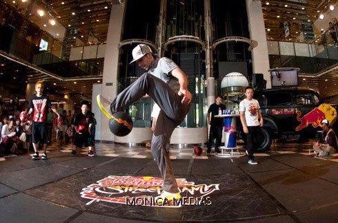 Un professionnel de foot freestyle realise des figures avec un ballon, son pied a la hauteur du genou