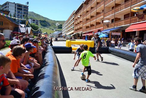 Des enfants lors d'une animation de footbal jouent au foot dans la rue dans un terrain delimite par des contours gonflables