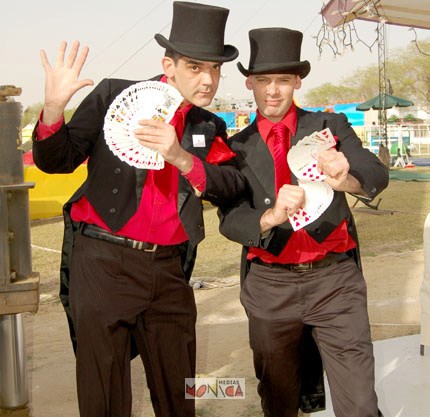 Ce duo de magiciens en tenue rouge et noire avec des chapeaux prepare un tour de magie avec des cartes