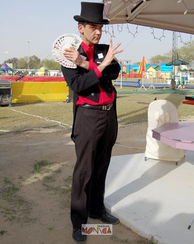 Ce magicien de carte avec sa tenue rouge et noire tient une paire de cartes sur sa main gauche